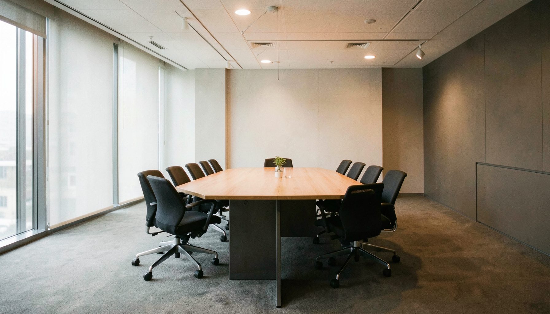 Quiet modern conference room with a long table and muted grey and warm orange tones, professional atmosphere.